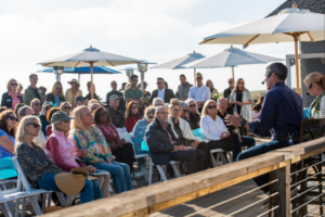 Audience listening to a speaker while sitting on an outdoor deck