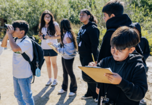 Group of middle school students with binoculars and clipboards