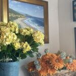 Framed artwork hanging on a wall near floral arrangements