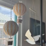 Decorative hot air balloons, seagulls, and a painting hung up by a window
