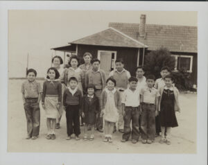 Group of Japanese children standing in front of a school house