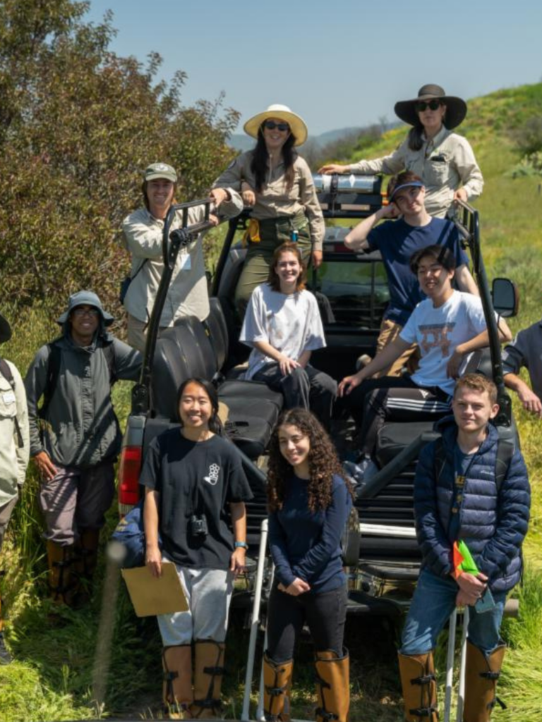 Students gathered around an off-road vehicle with State Park staff