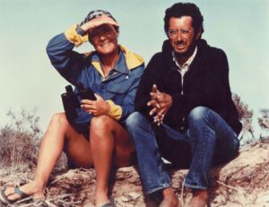 A man and woman sitting on the ground holding binoculars