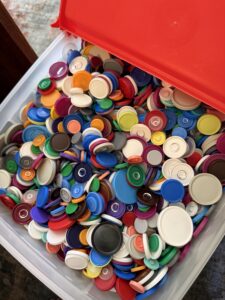 A container filled with multi-colored plastic bottle caps