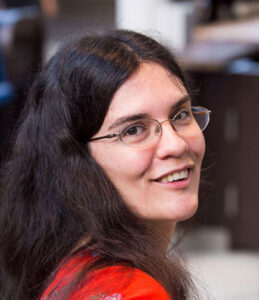 Woman with long, dark hair wearing glasses and a red shirt