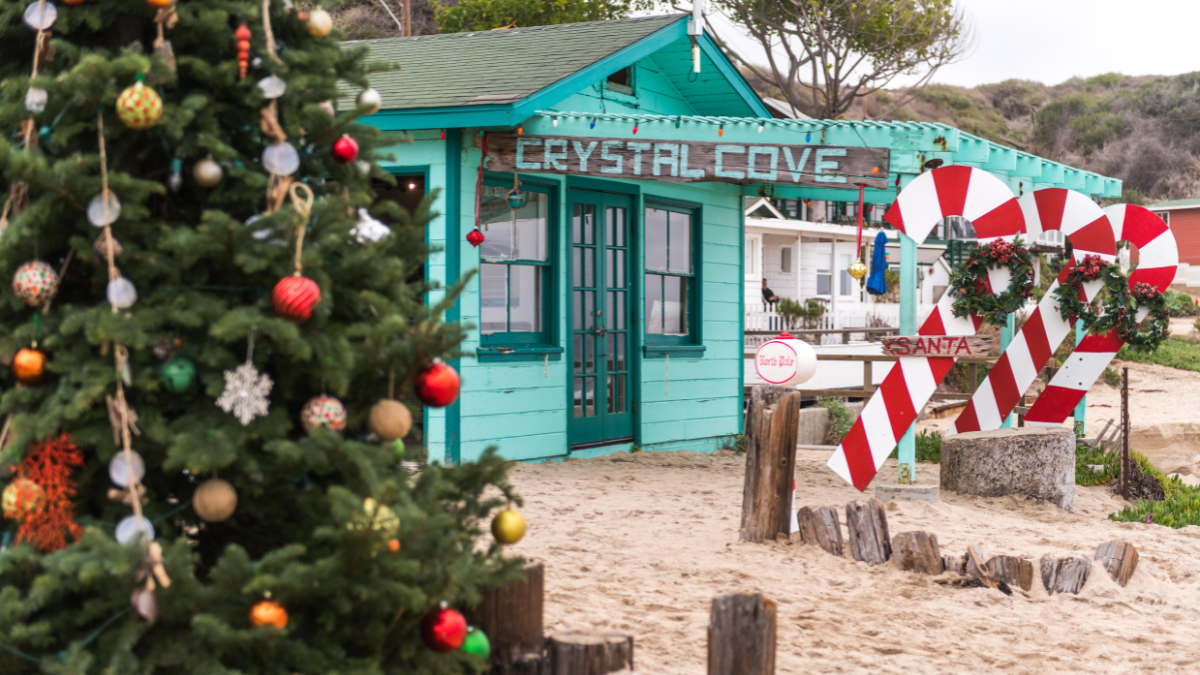 Teal cottage on the beach, decorated with large candy canes and a Christmas tree