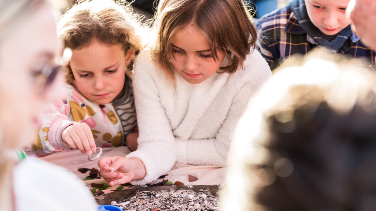 Group of children in sweaters making crafts with sea glass